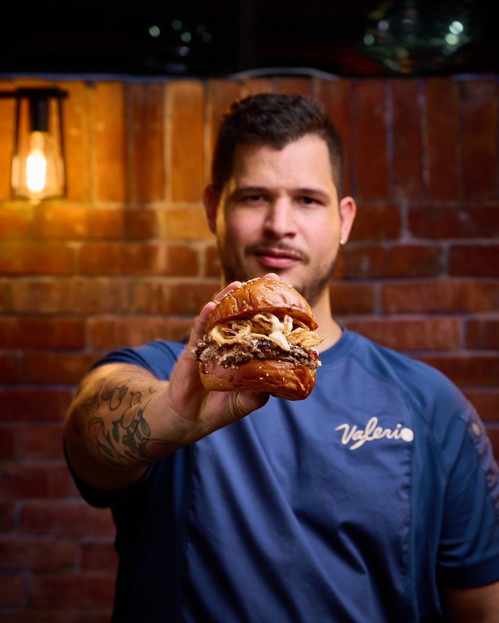 Andrés Valerio sosteniendo una hamburguesa de autor de Valerio Burger Club